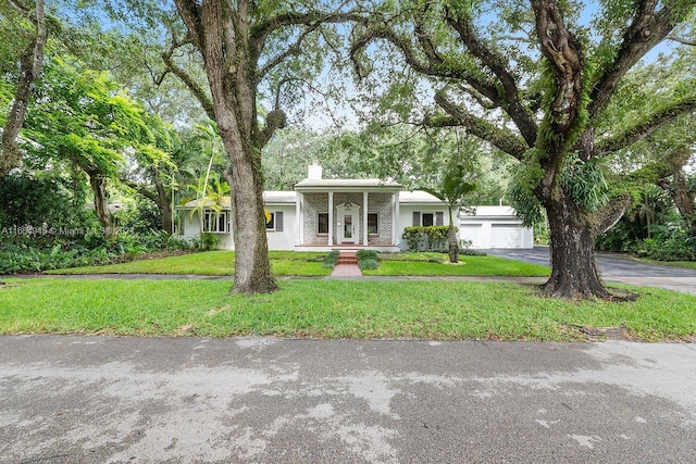 view of front facade with a front yard, a porch, a chimney, a garage, and aphalt driveway