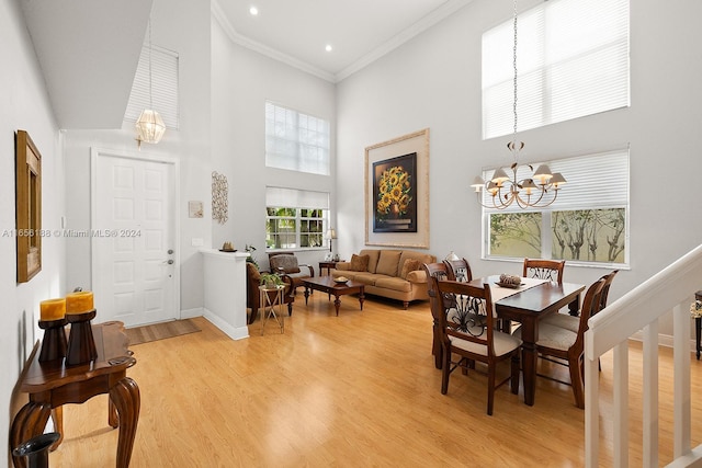 dining space featuring crown molding, a high ceiling, light wood-type flooring, and a chandelier