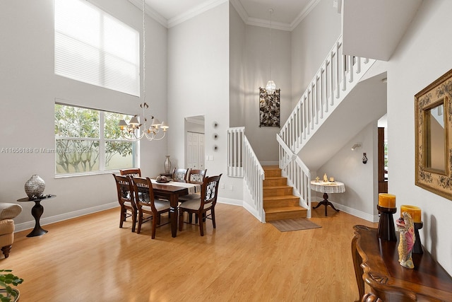 dining area featuring ornamental molding, a chandelier, a high ceiling, and light hardwood / wood-style floors