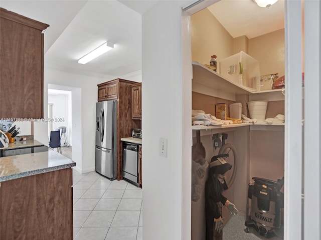 kitchen with light tile patterned floors, stainless steel appliances, and light stone countertops