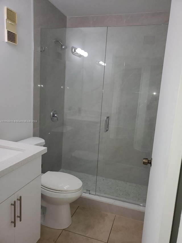 bathroom featuring vanity, toilet, a shower with shower door, and tile patterned floors