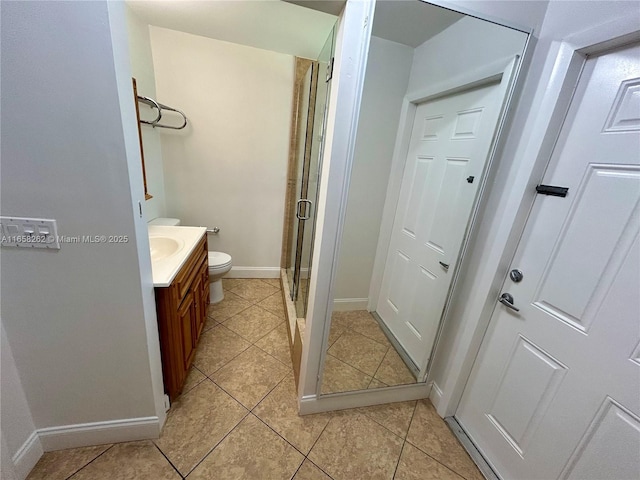 bathroom with tile patterned flooring, vanity, toilet, and walk in shower