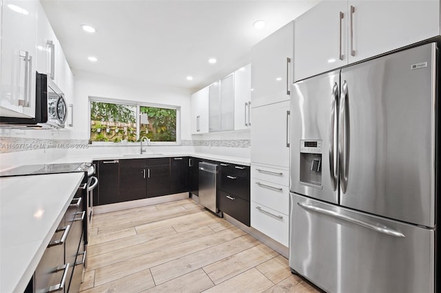 kitchen with white cabinets, stainless steel appliances, light countertops, and wood finish floors