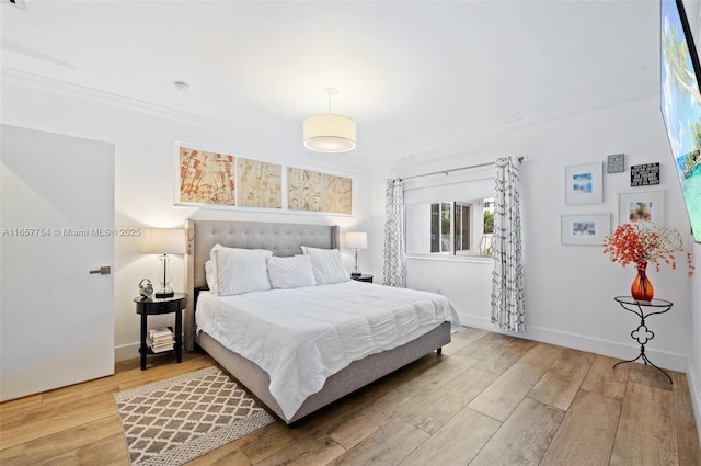 bedroom with ornamental molding, baseboards, and wood finished floors