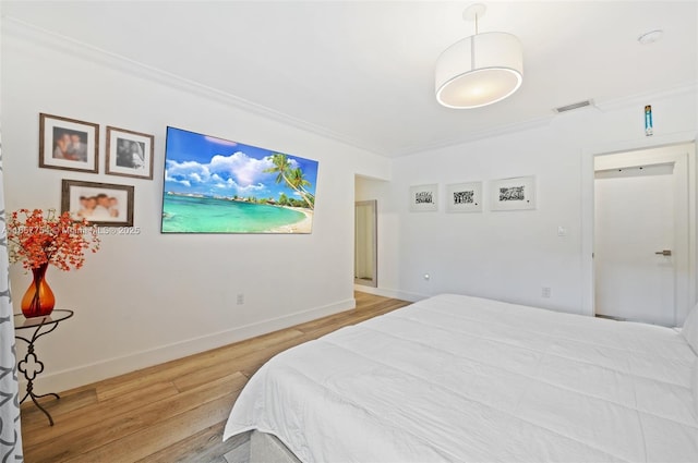 bedroom with visible vents, crown molding, light wood-type flooring, and baseboards