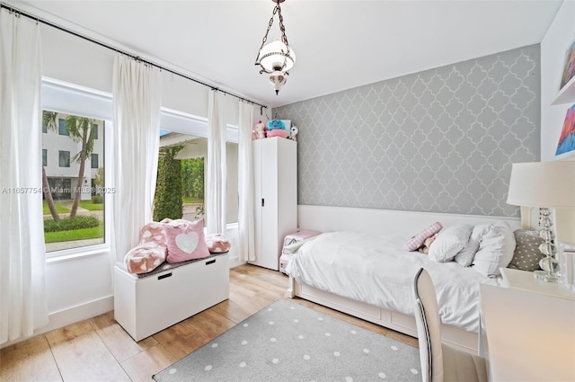 bedroom with wallpapered walls and light wood-type flooring