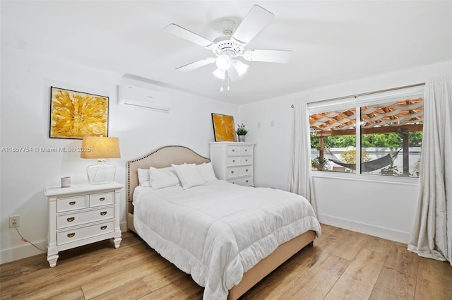 bedroom featuring ceiling fan, baseboards, light wood-style flooring, and a wall mounted AC