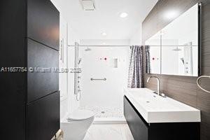 3551 E Glencoe St, Miami, FL 33133 - bathroom featuring a shower stall, vanity, and tile walls
