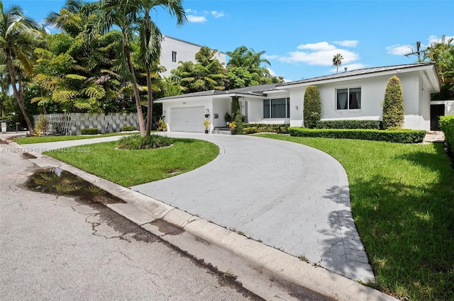 single story home featuring stucco siding, a front lawn, fence, concrete driveway, and an attached garage