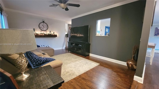 living room with crown molding, dark wood-type flooring, and ceiling fan