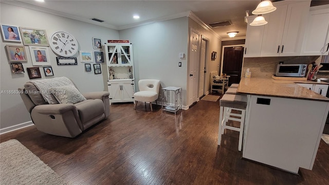 interior space with dark wood-type flooring, tasteful backsplash, white cabinetry, and a breakfast bar