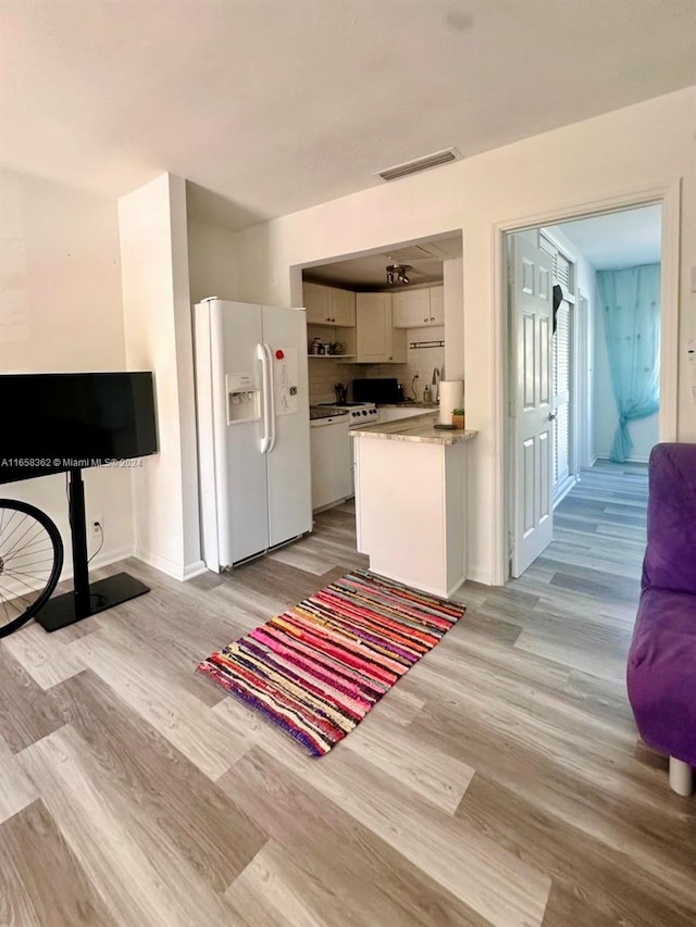 kitchen with white cabinets, white appliances, and light wood-type flooring