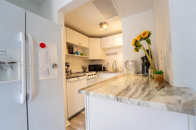 kitchen featuring light wood-type flooring, white cabinetry, kitchen peninsula, decorative backsplash, and white appliances