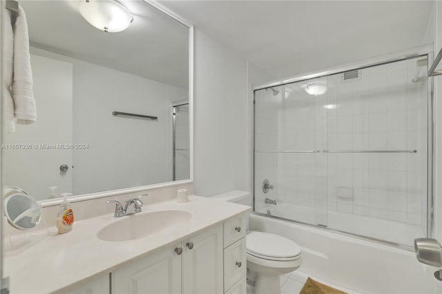 full bathroom with tile patterned floors, toilet, bath / shower combo with glass door, and vanity