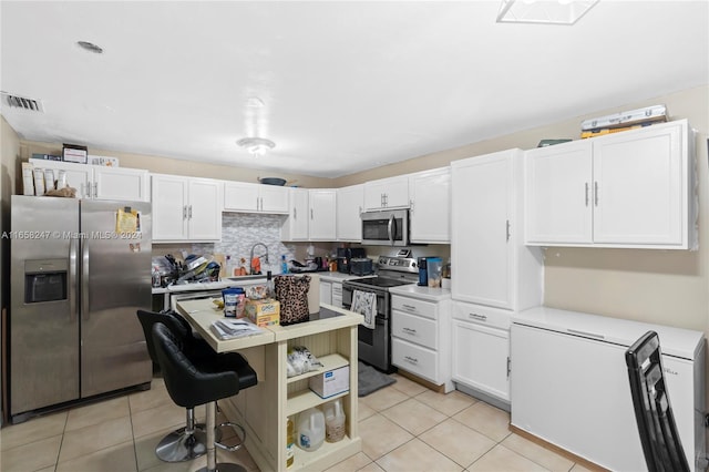 kitchen featuring light tile patterned floors, appliances with stainless steel finishes, tasteful backsplash, sink, and white cabinets