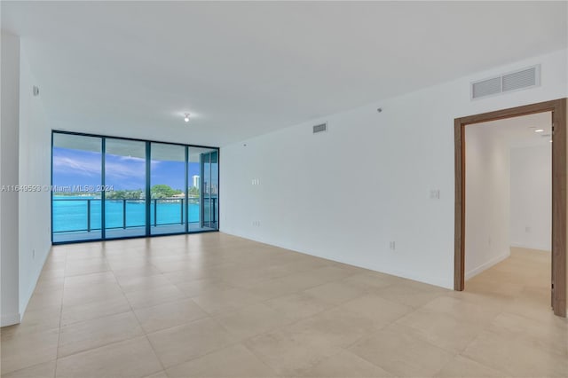 unfurnished room featuring a water view and a wall of windows