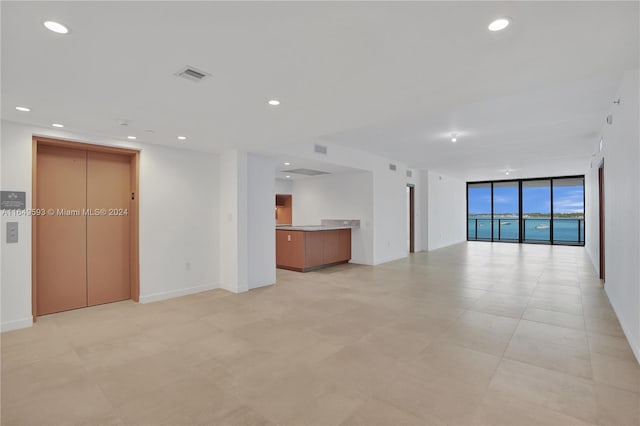 unfurnished living room featuring elevator and a wall of windows