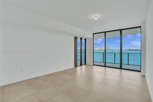 unfurnished room with a water view and expansive windows