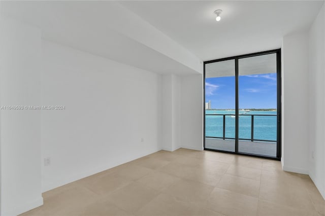 unfurnished room featuring a water view and expansive windows