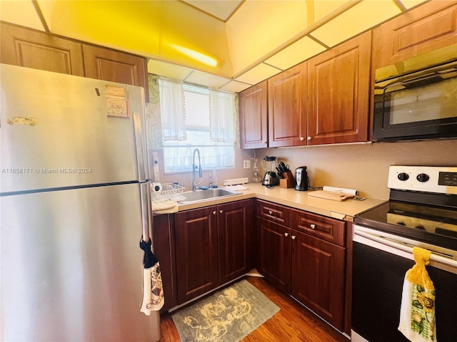 kitchen with dark hardwood / wood-style flooring, electric stove, sink, and stainless steel refrigerator