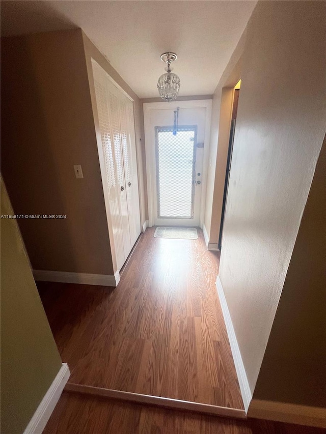 doorway with an inviting chandelier and wood-type flooring