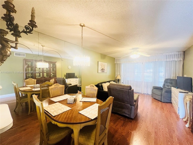 dining area featuring a textured ceiling, ceiling fan with notable chandelier, and hardwood / wood-style flooring