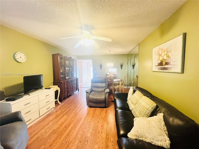 living room featuring ceiling fan, a textured ceiling, and light hardwood / wood-style flooring