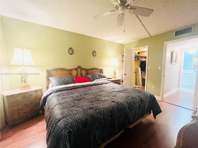 bedroom featuring a closet, light hardwood / wood-style floors, a textured ceiling, connected bathroom, and ceiling fan