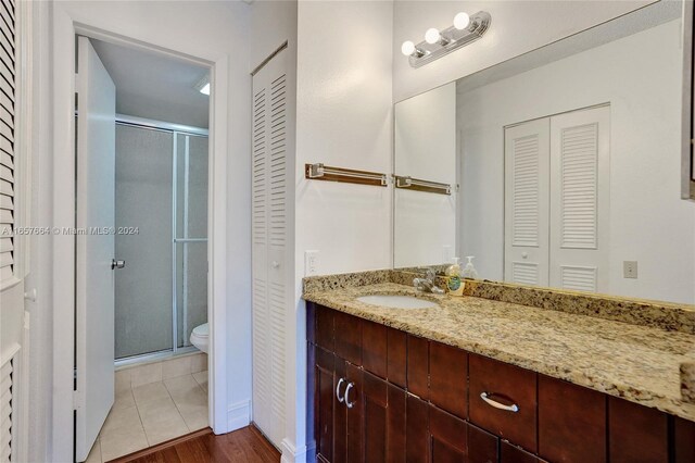 bathroom featuring a shower with shower door, hardwood / wood-style floors, toilet, and vanity