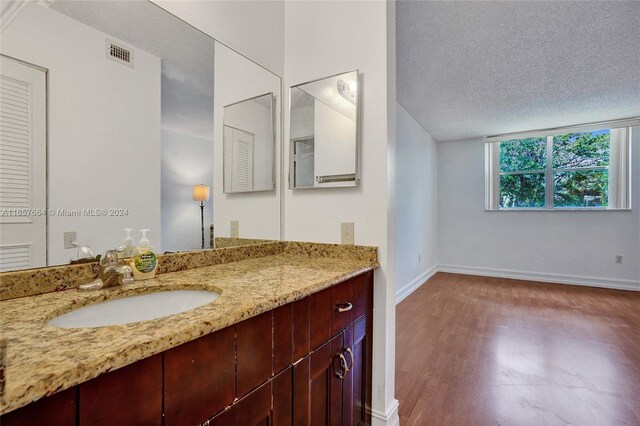 bathroom with a textured ceiling, vanity, and wood-type flooring