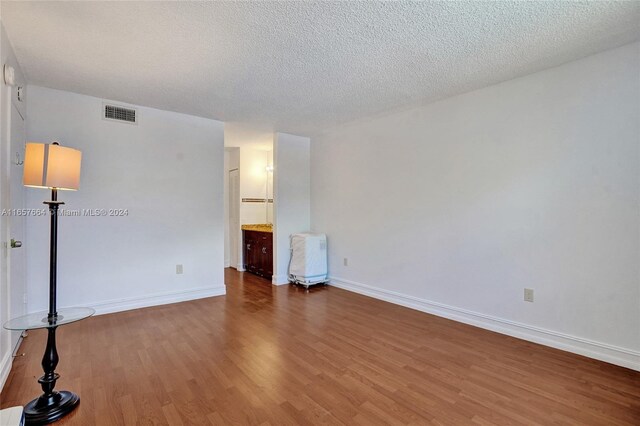 empty room with wood-type flooring and a textured ceiling