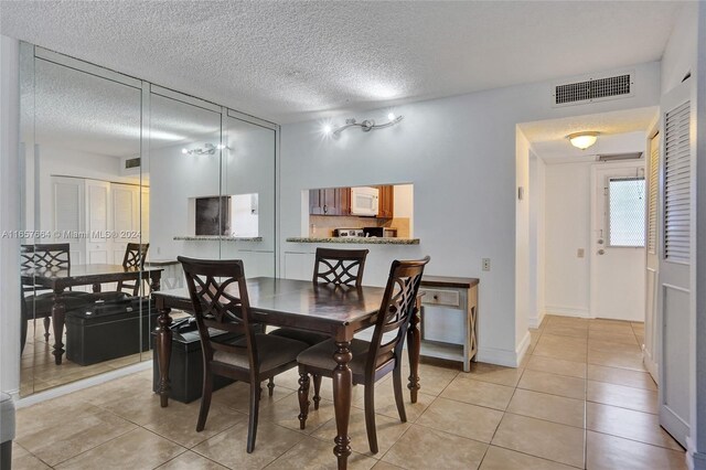 tiled dining space featuring a textured ceiling