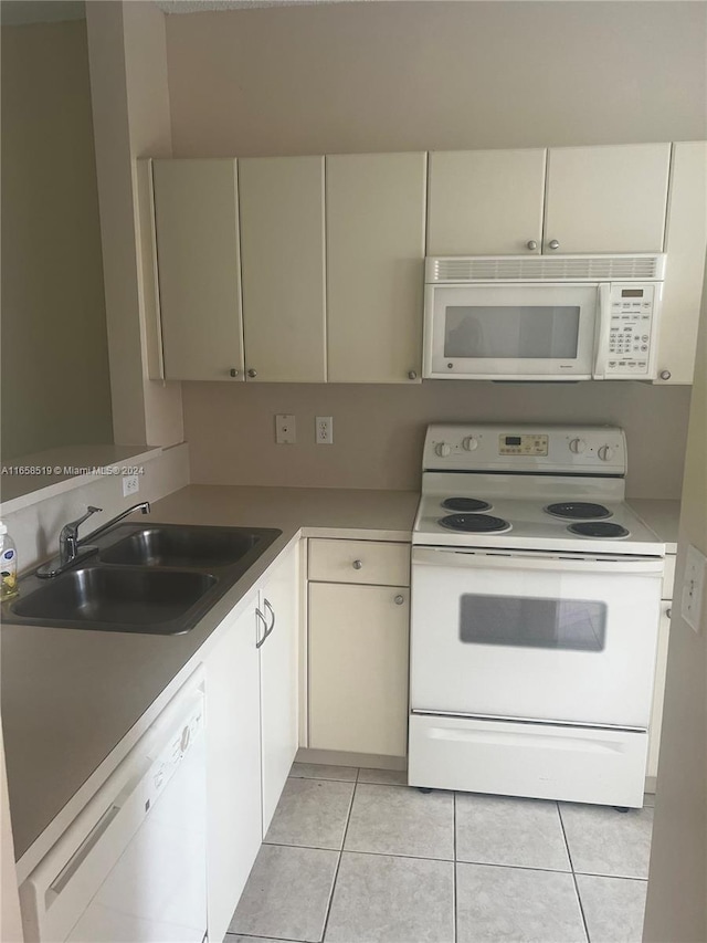 kitchen featuring light tile patterned floors, white appliances, and sink