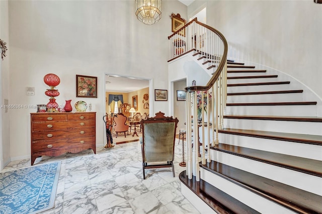 staircase with a high ceiling and a chandelier