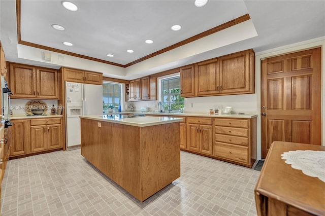 kitchen featuring a tray ceiling, ornamental molding, a kitchen island, and white refrigerator with ice dispenser