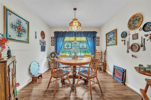 dining area featuring wood-type flooring and a notable chandelier