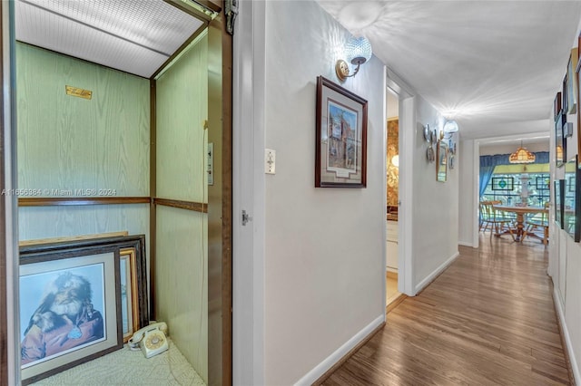 hall with a barn door, hardwood / wood-style floors, and elevator