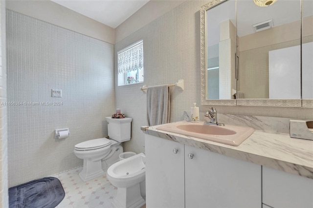 bathroom featuring toilet, a bidet, and vanity