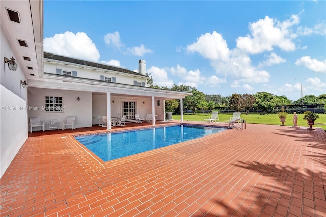 view of pool with french doors, a patio area, and a yard