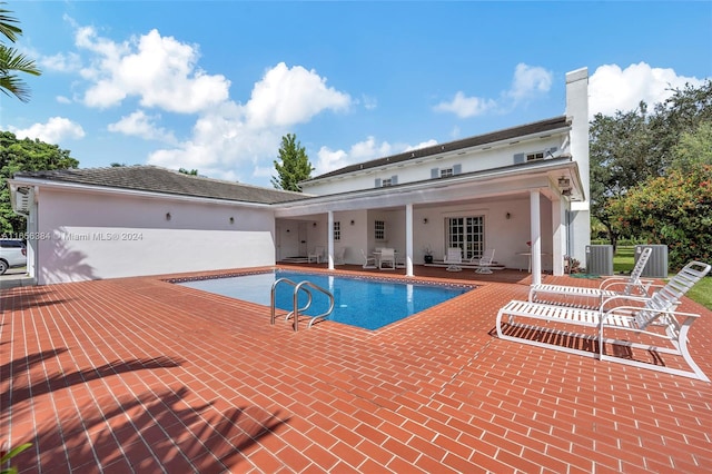 view of swimming pool featuring cooling unit, a patio area, and french doors