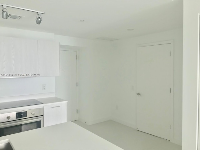 kitchen featuring rail lighting, white cabinetry, black electric cooktop, light countertops, and oven
