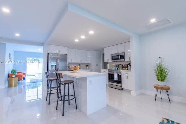 kitchen featuring a center island, stainless steel appliances, white cabinetry, and a breakfast bar