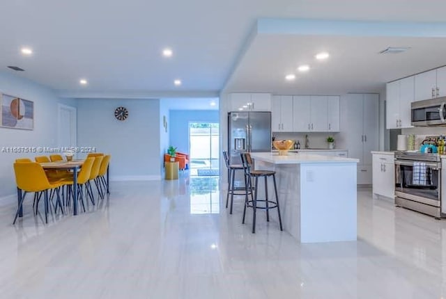 kitchen featuring white cabinetry, a kitchen island, stainless steel appliances, and a kitchen breakfast bar