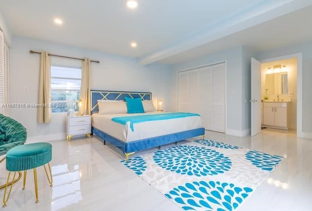 bedroom featuring a closet, connected bathroom, beamed ceiling, and sink