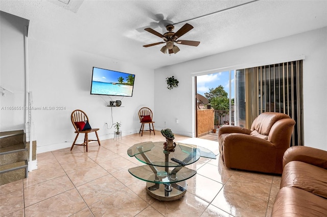 living room with ceiling fan, light tile patterned floors, and a textured ceiling