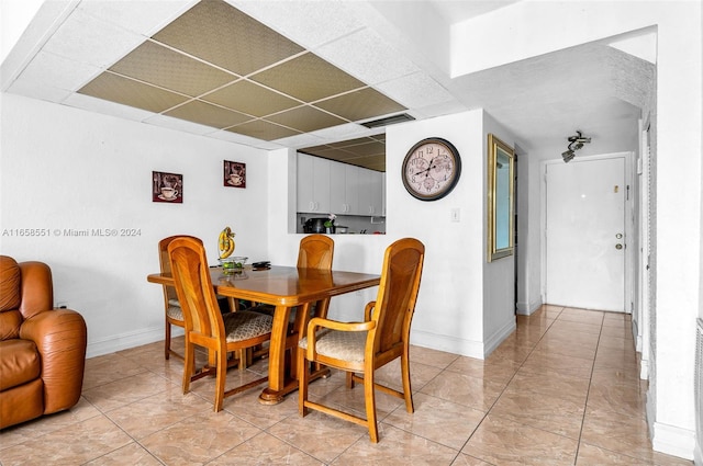 tiled dining area featuring a paneled ceiling