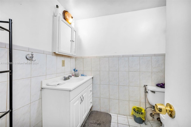 bathroom featuring tile patterned floors, vanity, toilet, and tile walls