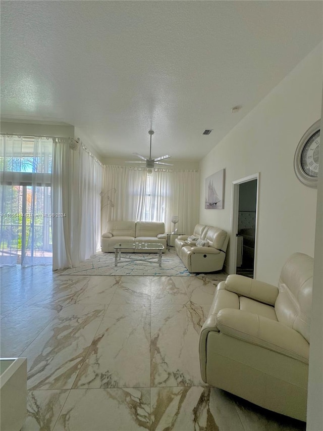 living room with ceiling fan and a textured ceiling