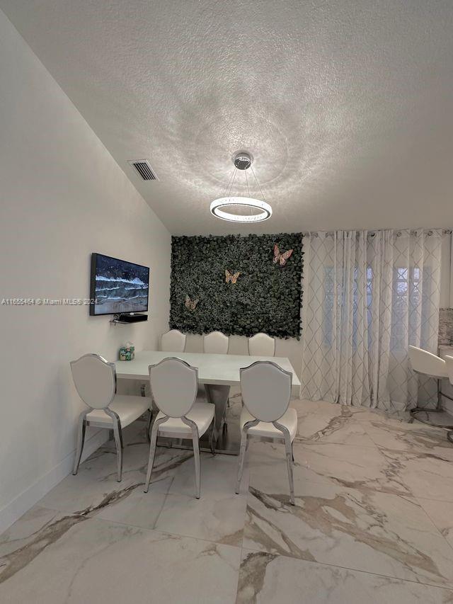 unfurnished dining area with a textured ceiling and vaulted ceiling