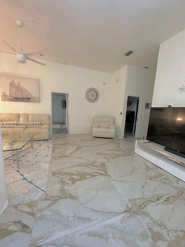 living room with a textured ceiling and ceiling fan